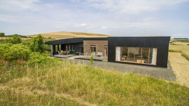 A modern building with a patio area featuring outdoor furniture. - The Old Signal House (Ventnor)
