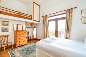 A bedroom with a bunk bed, wooden dresser, and a large window with curtains. - The Old Signal House (Ventnor)
