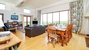A spacious living room with a large dining table, a sofa, and a bookshelf. - The Old Signal House (Ventnor)