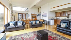 A spacious living room with a large window, a fireplace, and a dining area. - The Old Signal House (Ventnor)