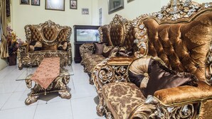 Ein luxuriöses Wohnzimmer mit aufwendigen Möbeln, einem Fernseher und einer dekorativen Vase.