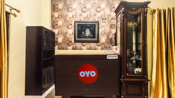Ein Empfangstresen mit dem 'OYO'-Logo, einem Bild in einem Rahmen darüber und einem Schrank mit Glastüren zur Rechten.
