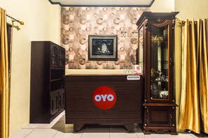 Een receptiebalie met een 'OYO' logo, een lijst met foto erboven en een kast met glazen deuren aan de rechterkant.