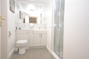 Un baño moderno con inodoro, tocador y ducha.