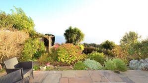 Un jardin agrémenté d’une pergola, d’une terrasse en pierre et de diverses plantes.
