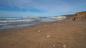 A sandy beach with white cliffs in the background and a clear sky.