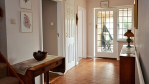 A hallway with wooden flooring, white doors, and a table with a bowl of pinecones.