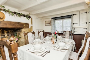 Une salle à manger avec une table blanche dressée pour un repas, entourée de chaises en bois.