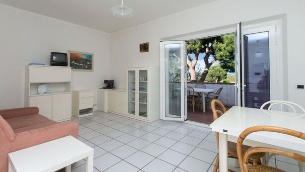 Un salon moderne comprenant un canapé, une table basse, un téléviseur et une porte-fenêtre coulissante donnant sur une terrasse extérieure.