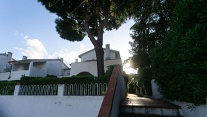 Un quartier résidentiel avec un escalier menant à un bâtiment blanc, entouré de verdure et d’une clôture.