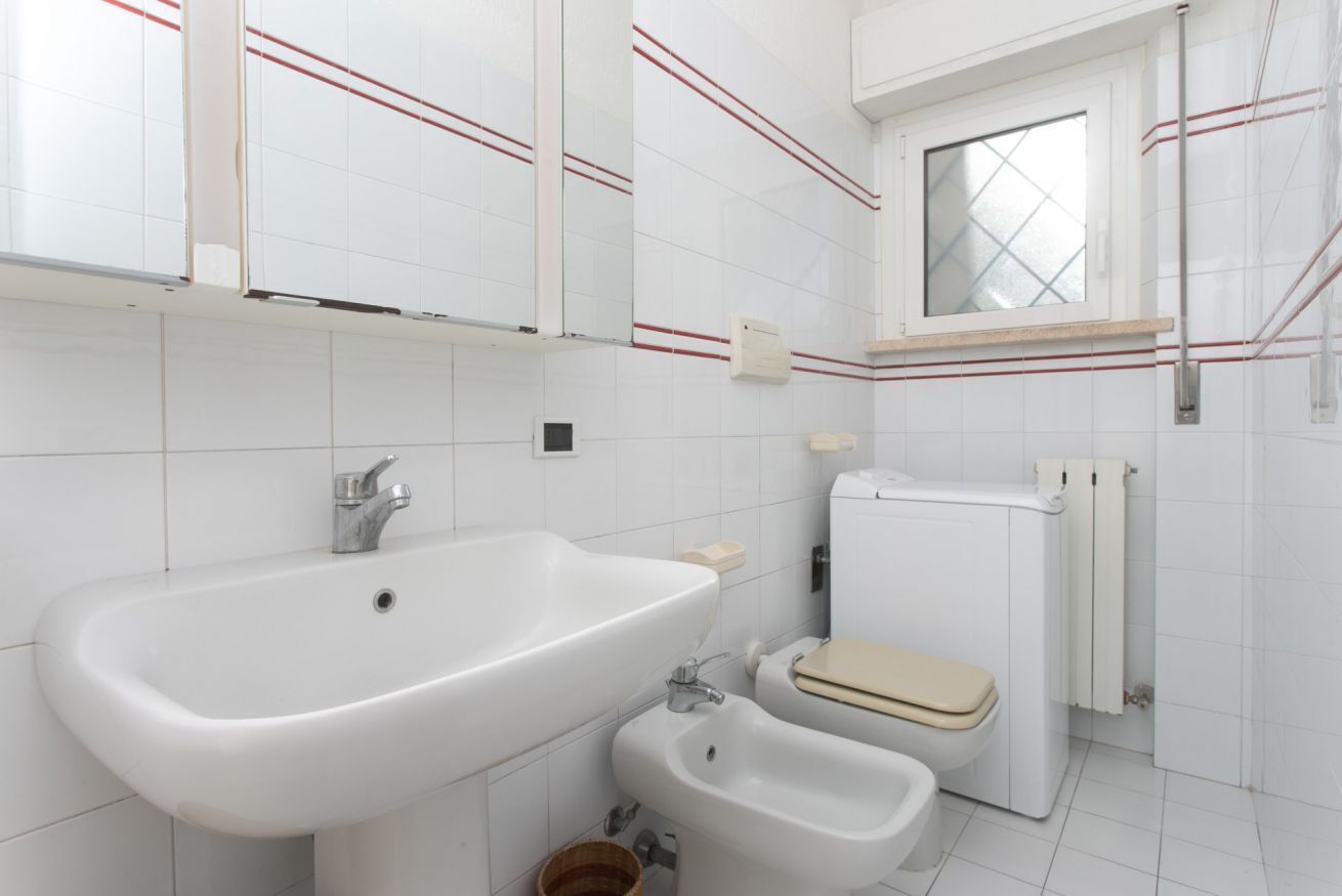 Une salle de bain avec un grand lavabo, un bidet, des toilettes et une fenêtre.