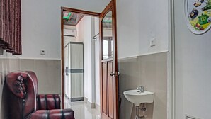 Een badkamer met een houten deur, een witte wastafel en een rode lederen fauteuil.