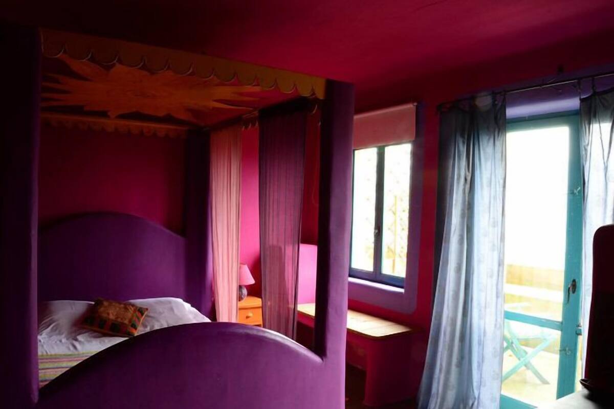 A room with a bed, a desk, and a window with curtains.