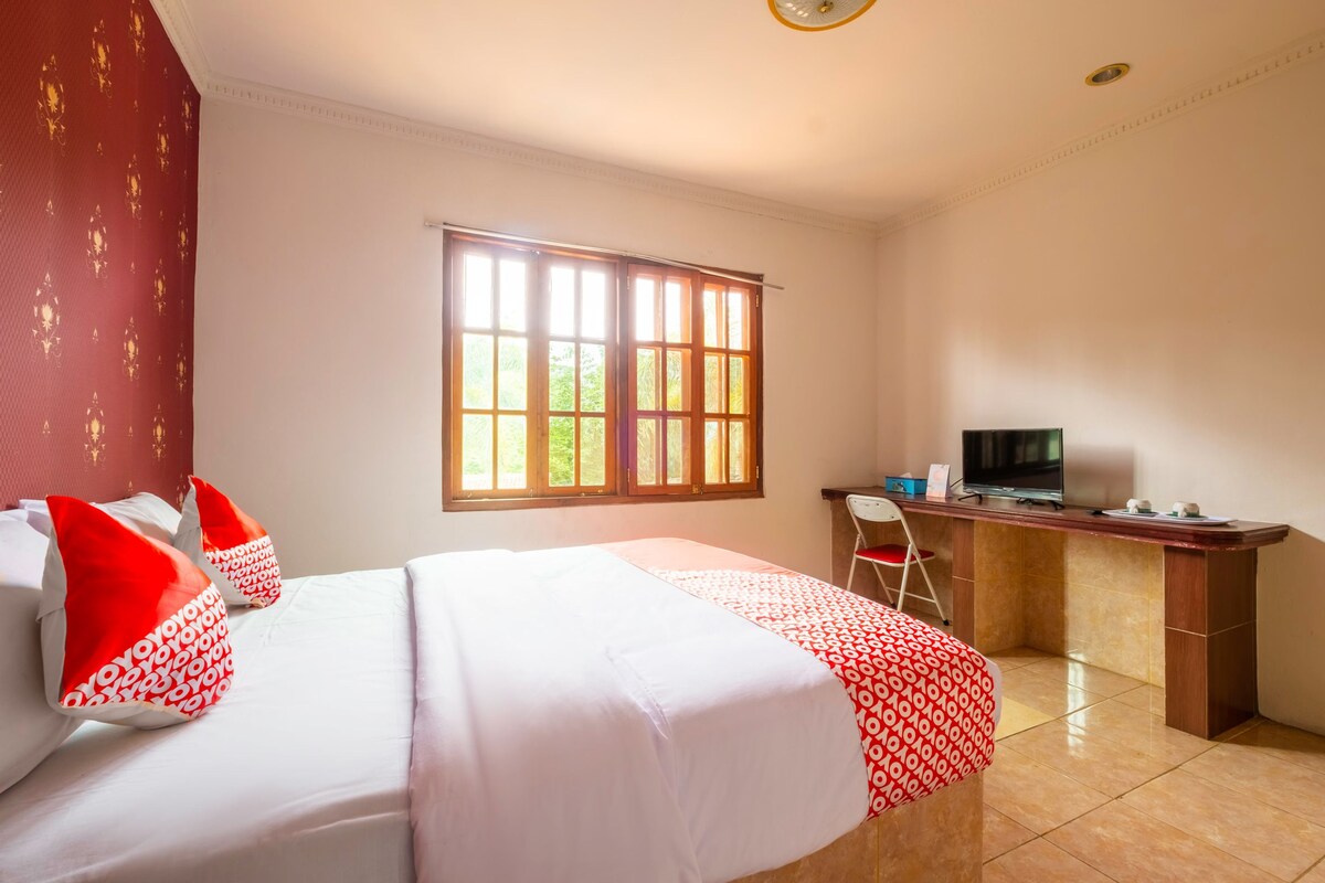 A hotel room with a bed, a desk, a chair, and a television.