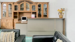 A living room with a wooden cabinet, a flat-screen TV, and a vase with flowers. - OYO 2301 Hocky Guest House (Banjarmasin)