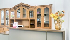 A reception area with a wooden cabinet, a vase with flowers, and a sign. - OYO 2301 Hocky Guest House (Banjarmasin)