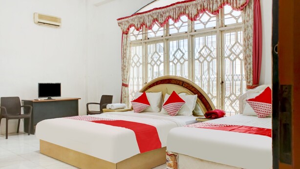 A hotel room with two beds, a desk with a computer, and a chair. - OYO 2301 Hocky Guest House (Banjarmasin)