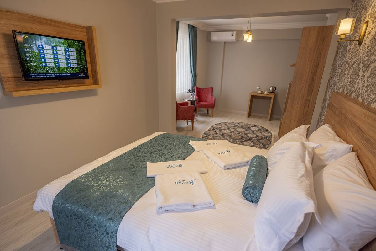 A hotel room with a bed, a TV mounted on the wall, a small table, and a chair.