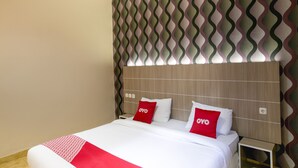 Een hotelkamer met een bed, een houten hoofdeinde en een behang met patroon.