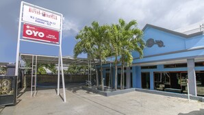Een hotel met een blauwe gevel, palmbomen en een bord waarop Hotel Charvita staat.