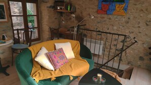 Um quarto acolhedor com uma poltrona verde, uma mesinha com velas e uma parede de pedra rústica.