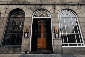 A building with a large arched window, a wooden door, and two plaques on the wall. - Brewdog Kennels Aberdeen (Aberdeen)