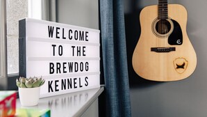 A lightbox with "WELCOME TO THE BREWDOG KENNELS" message, a guitar, and a potted plant on a window sill. - Brewdog Kennels Aberdeen (Aberdeen)