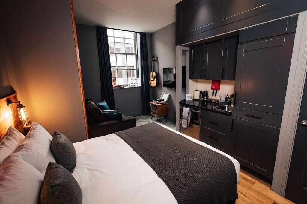 Et moderne hotelværelse med en stor seng, et skrivebord og et tekøkken.