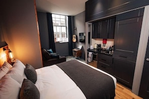 A modern hotel room with a large bed, a desk, and a kitchenette. - Brewdog Kennels Aberdeen (Aberdeen)
