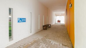 A corridor with a parking sign, benches, and a brick floor. - OYO 2228 Arwinda Costel (Cianjur)