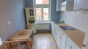 Une cuisine équipée d’une table à manger, de chaises, d’une fenêtre, de placards et d’un évier.