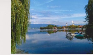 Un lac paisible, avec des bateaux, une église et un pont en arrière-plan.