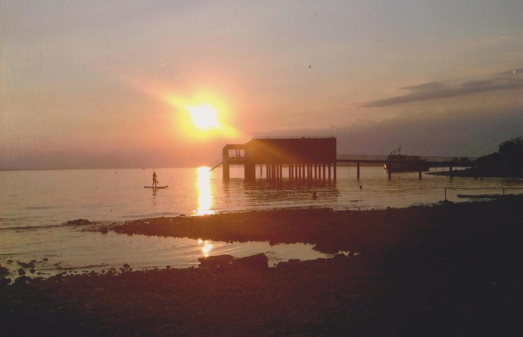 Une jetée s’avançant dans des eaux calmes au coucher du soleil.