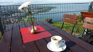A wooden table with a white cup of coffee, a vase with a white flower, and a red placemat. - Cozy, homely apartment (Lindau-Bodolz)