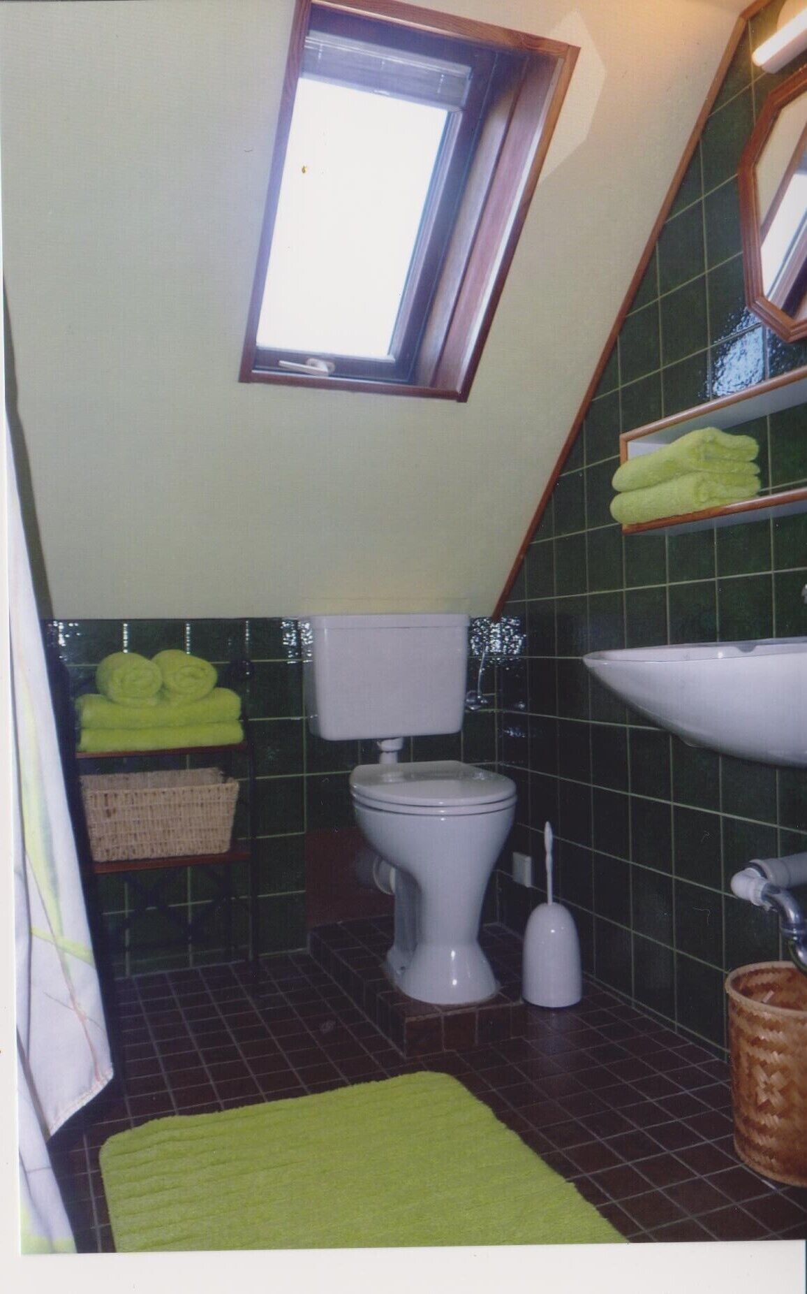 Ein kleines, schmales Badezimmer mit Toilette, Waschbecken und Fenster.