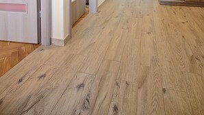 A hallway with wooden flooring, a wooden wardrobe, and a door with a circular decoration. - Victus Apartmenty - Jantar (Sopot)