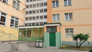A multi-story residential building with a green entrance and a visible staircase leading to the entrance. - Victus Apartmenty - Jantar (Sopot)