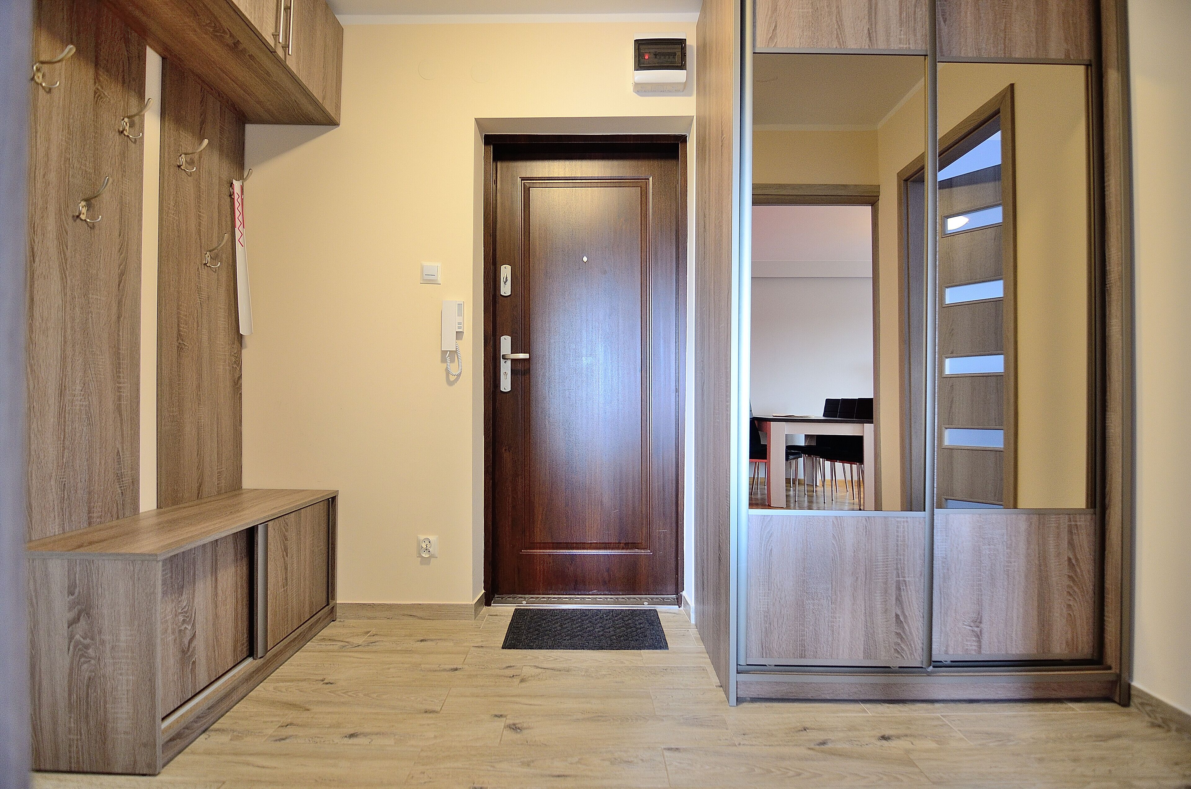 A hallway with a wooden door, a coat rack, and a built-in cabinet.