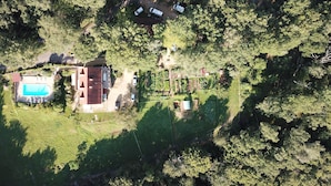 Vista aerea di una proprietà con piscina, un edificio con tetto rosso e un giardino recintato.