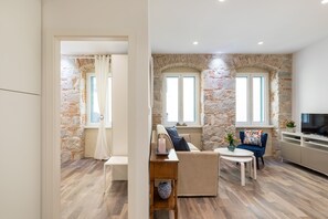 A modern living room with a stone wall, a sofa, a coffee table, and a TV.