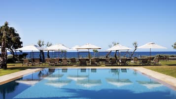 Una piscina al aire libre, camas de piscina con cargo, sombrillas