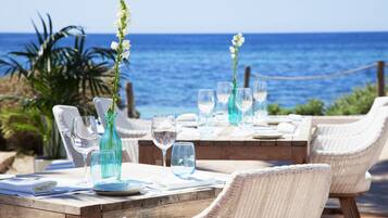 Zona pranzo all'aperto con sedie e tavoli in vimini, con vista sull'oceano.