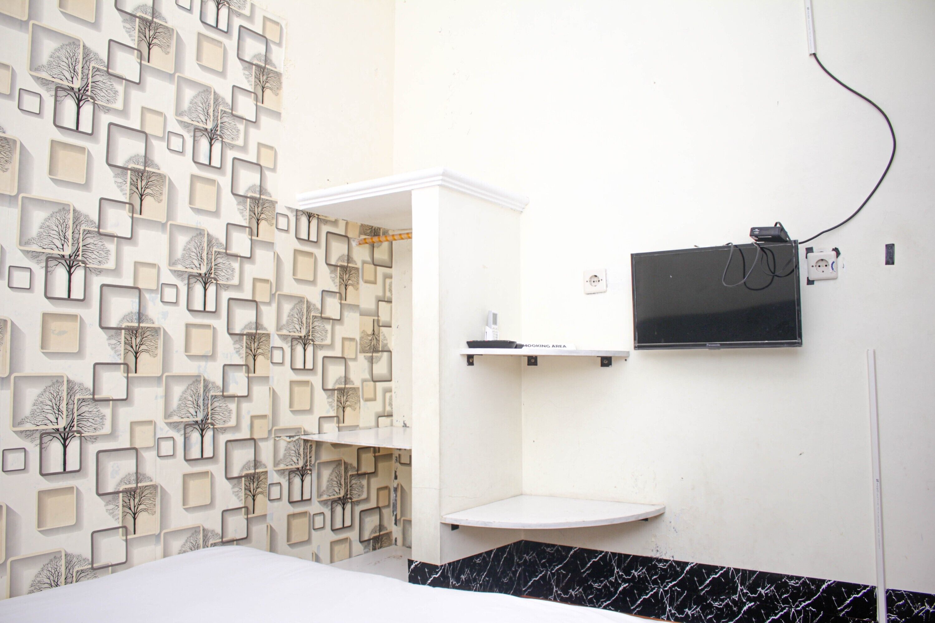 Un baño con pared estampada, un lavamanos blanco y un espejo negro.