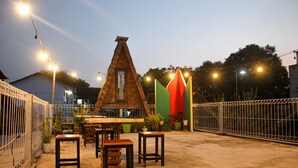 An outdoor patio with a brick structure, tables, chairs, and potted plants. - Capital O 2258 Santana Syariah Guest House (Surakarta)