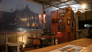 A restaurant interior with a large mural of a temple, wooden furniture, and a menu board. - Capital O 2258 Santana Syariah Guest House (Surakarta)