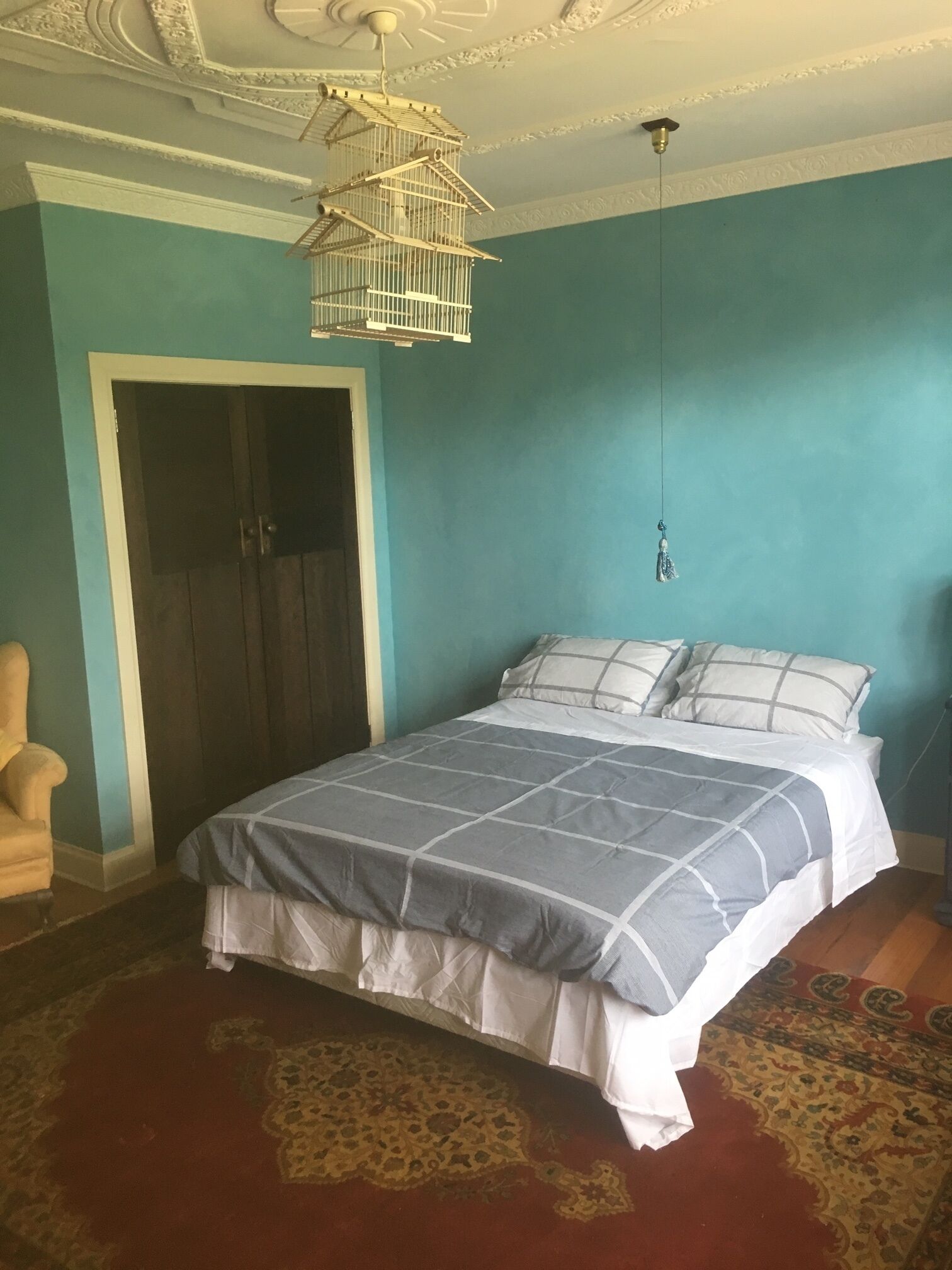 Une chambre à coucher avec un lit, une chaise, un luminaire suspendu et une porte.