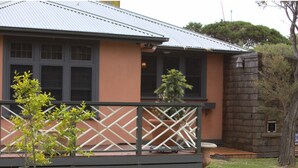 Ein Haus mit Veranda, kleinem Garten und einem Baum.