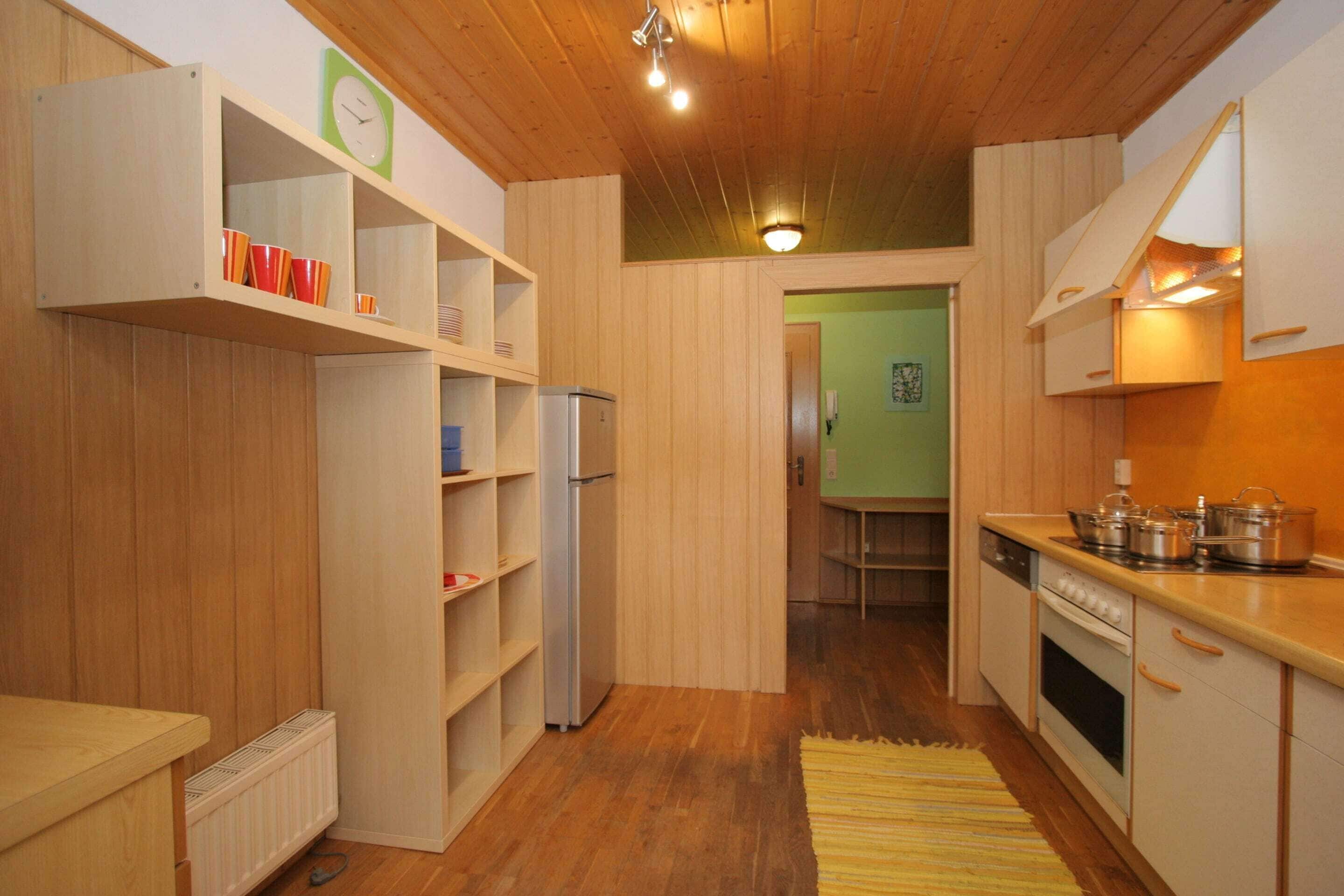 Une cuisine de taille réduite, dotée de meubles en bois, d’un réfrigérateur encastré et d’une cuisinière.