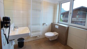 A bathroom with a sink, toilet, and window.