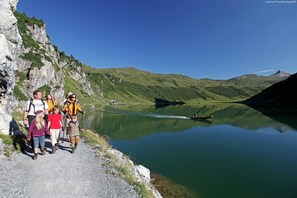 A group of people on a hiking trail beside a calm lake with mountains in the background. - Apartment in Kleinarl Near Ski Lift (Kleinarl)